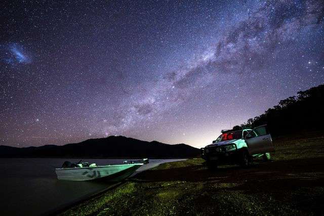 Photograph of a tinny launched on lake Eildon at night with the milky way illuminating the sky